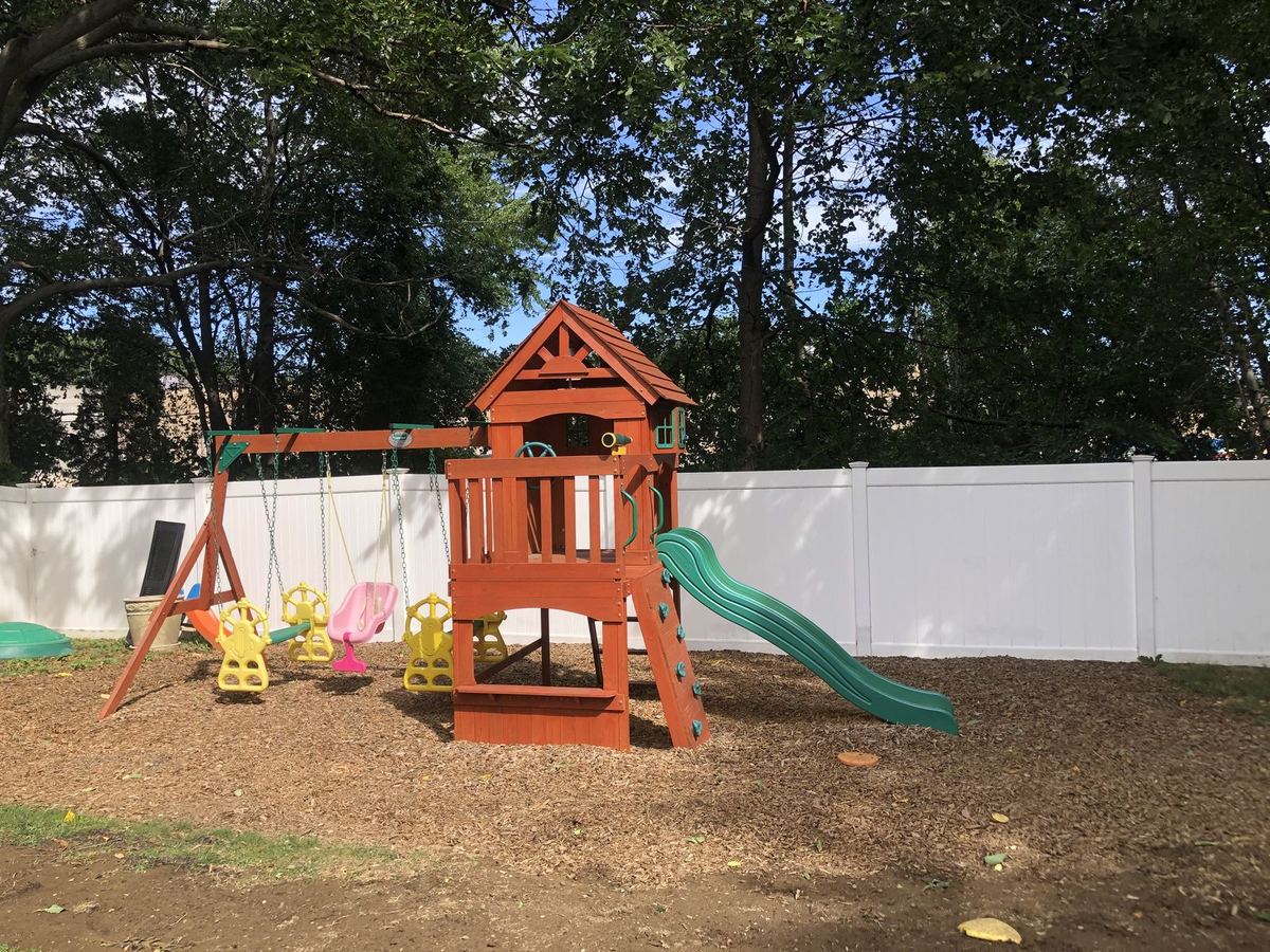 The fenced back yard: a wooden play set with swings, a slide and a lookout tower